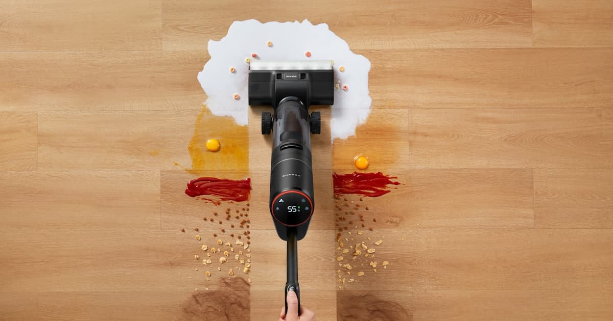 A cordless vacuum cleaner picking up spilled condiments and cereal on a wood floor
